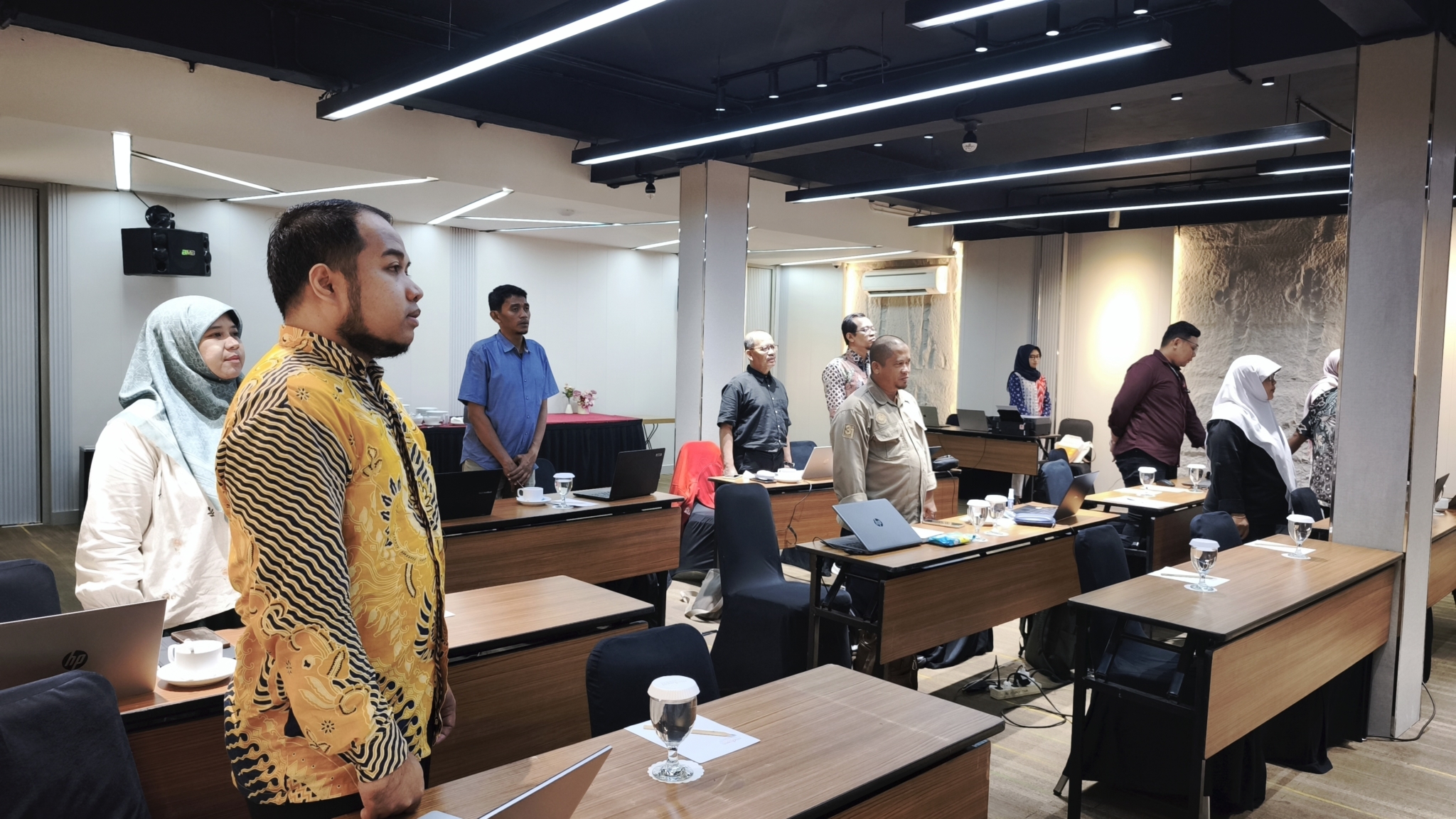 Seluruh peserta workshop berdiri menyanyikan Mars Universitas Mulia dalam suasana khidmat saat seremonial pembukaan kegiatan di Ruang Townhall Midtown Express Hotel, Rabu (30/7/2025). (Humas Universitas Mulia)