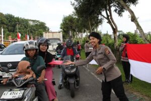Anggta Polwan Polda Kaltim membagikan bendera ke pengendara di Balikpapan / Polda Kaltim